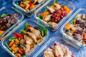 A top view of several dishes including meat, beans, vegetables and sauces in casseroles on a table